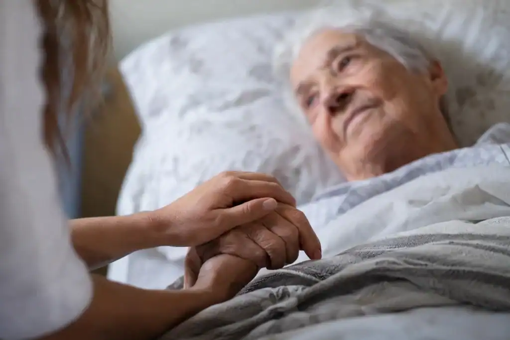 Persona mayor con Alzheimer en fase terminal acompañada por una cuidadora